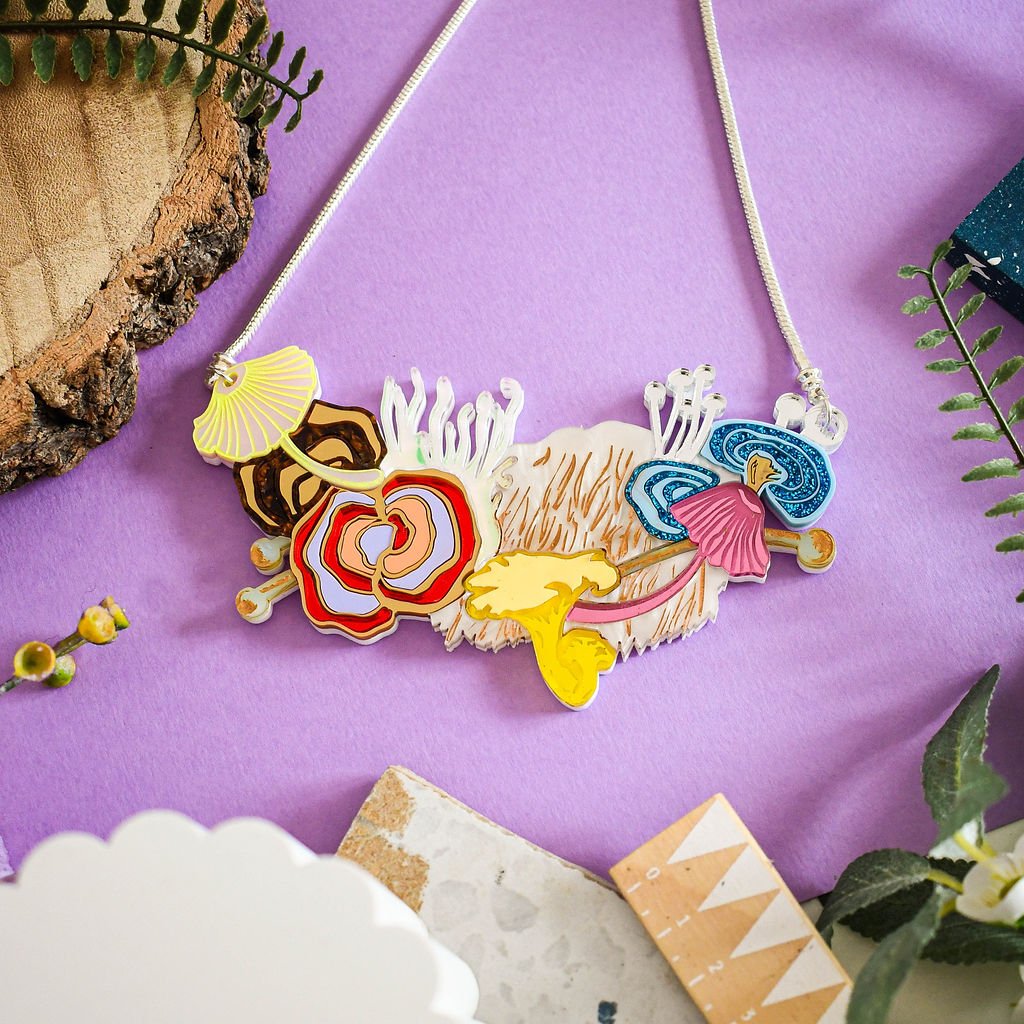 A colorful statement necklace with mushroom shapes displayed on a purple background.