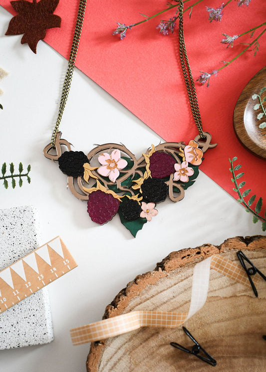 Decorative necklace with brambles and floral elements on a white surface with autumnal decorations.
