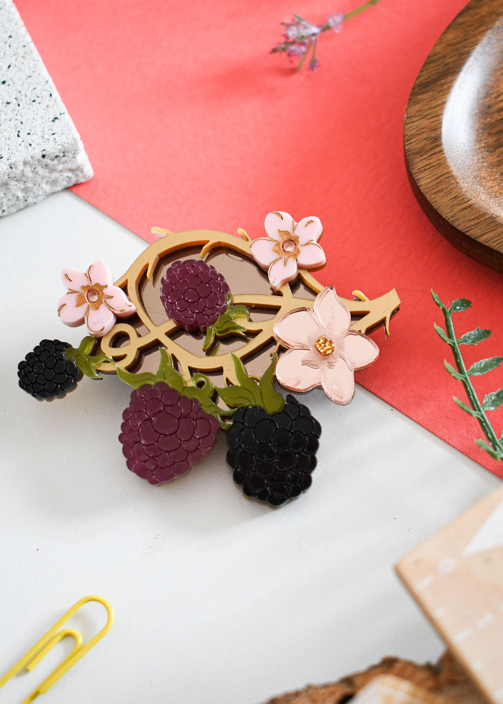 Decorative brooch with flowers and berries on a red and white background